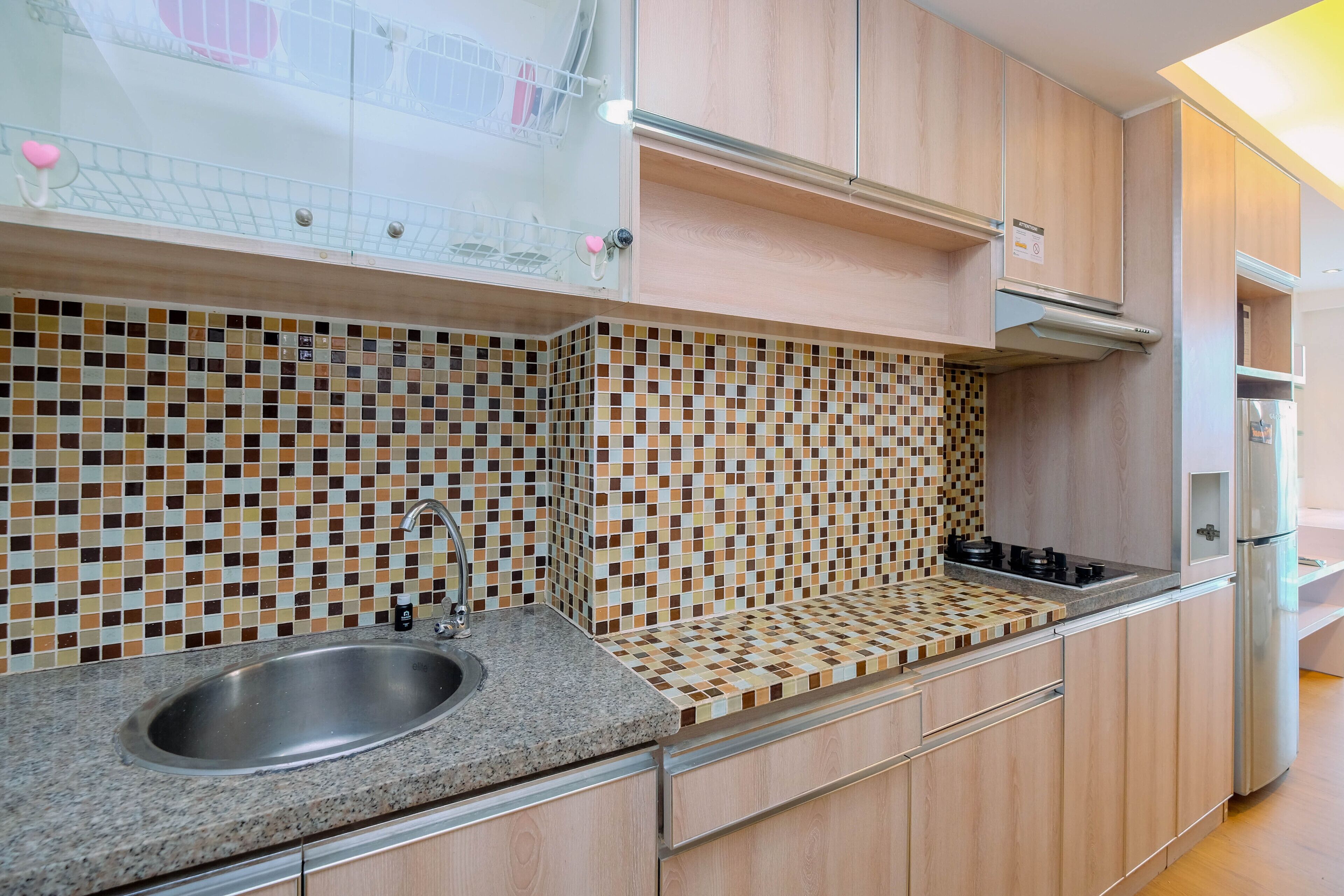 Cuina amb frontissa de rajola, rentamiques d'acer inoxidable, armaris de fusta i forn de mur.
