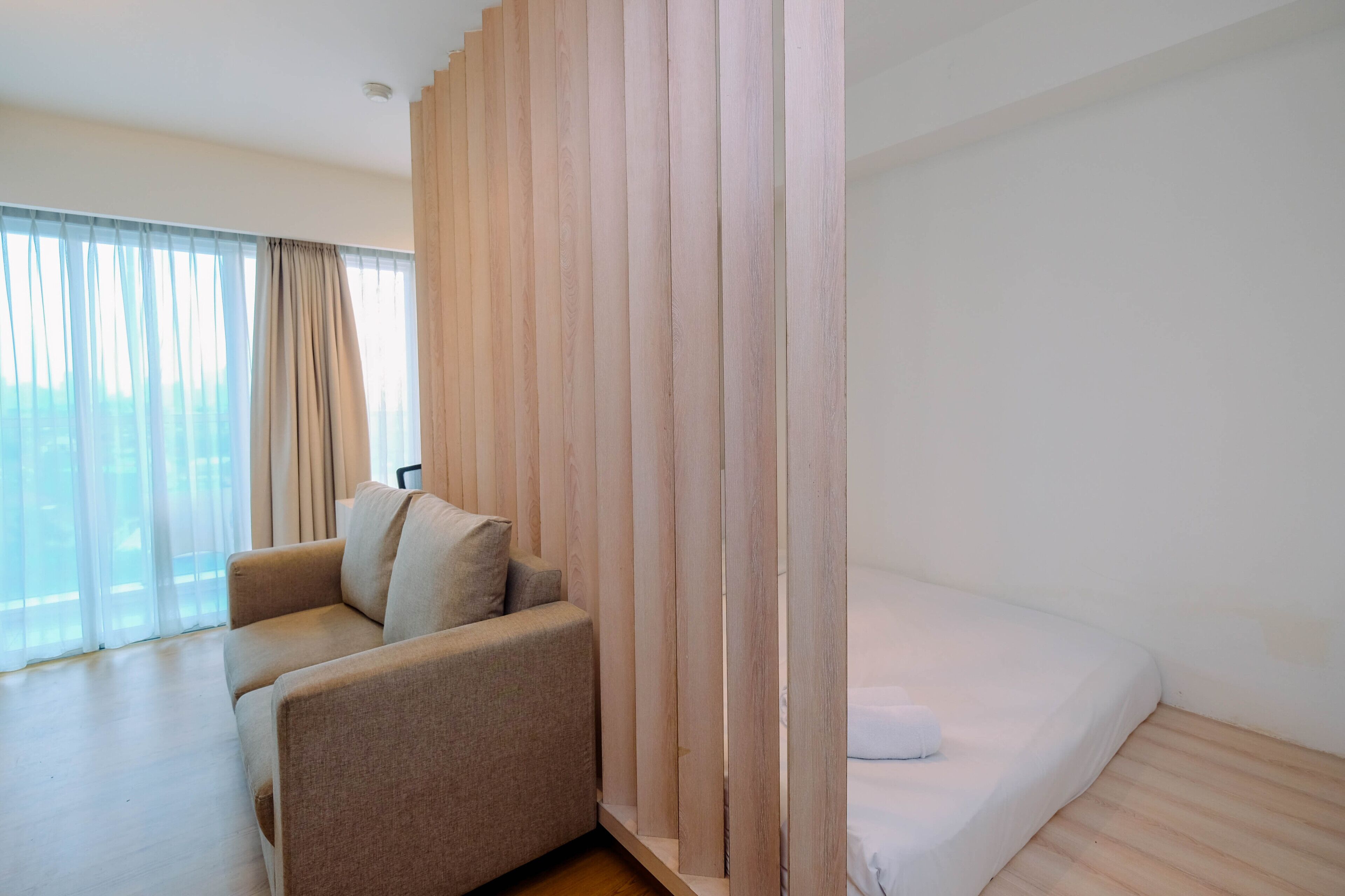 A modern hotel room with a sofa, a bed, and a wooden partition.