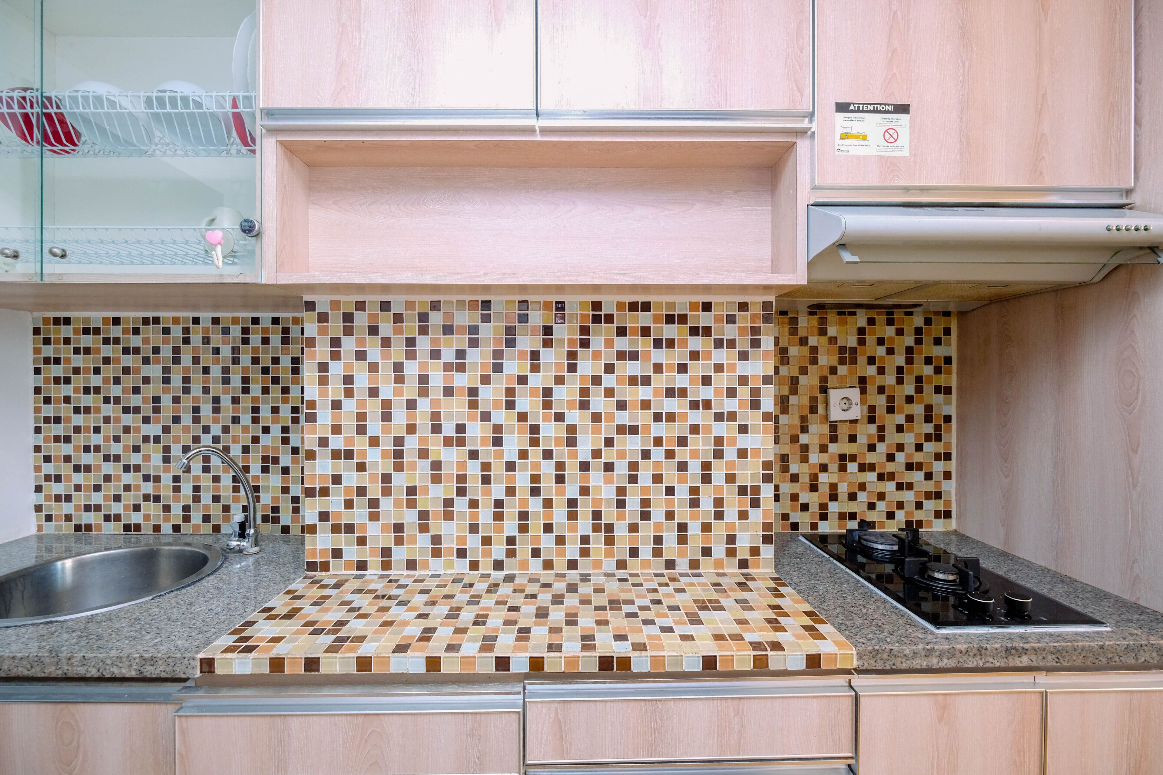 A kitchen with a tiled backsplash, stainless steel sink, and a gas stove.