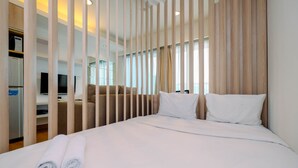 A hotel room with a bed, a TV, a sofa, and a wooden partition. - Nice Living Studio At 8Th Floor Tamansari The Hive Apartment (Jakarta)