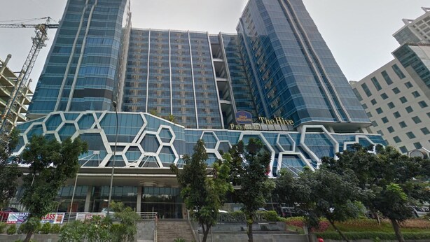 A modern hotel with a distinctive geometric facade, multiple high-rise buildings in the background, and a well-maintained outdoor area with trees. - Nice Living Studio At 8Th Floor Tamansari The Hive Apartment (Jakarta)