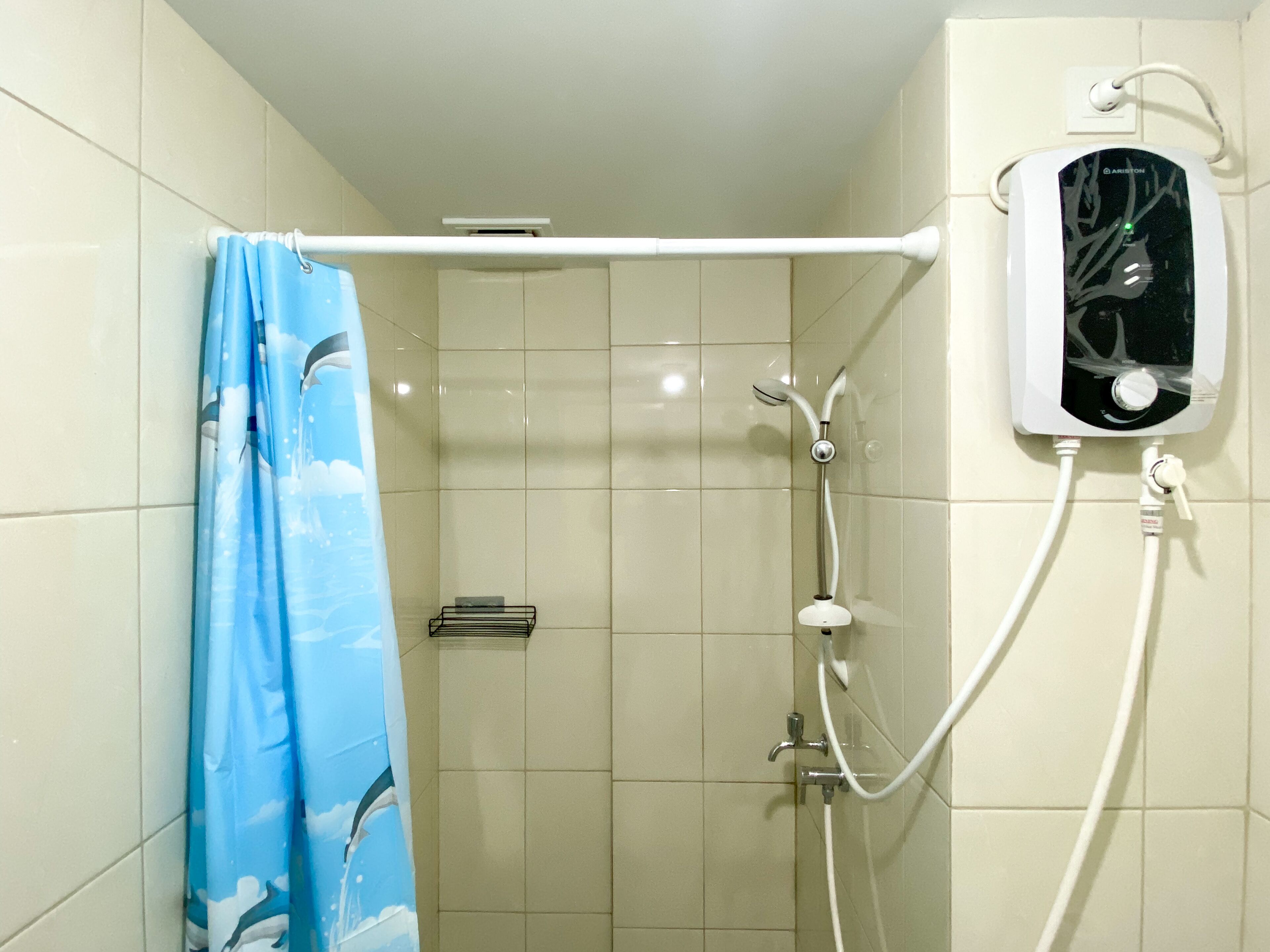 Ducha con cortina, calentador de agua instalado en la pared y ducha de mano.