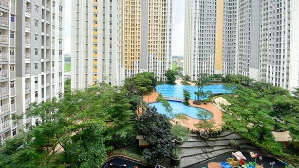 A high-rise residential building complex with a central swimming pool surrounded by greenery and a playground. - Elegant And Comfy 2Br Springlake Summarecon Bekasi Apartment Near Summarecon Mall (Bekasi)