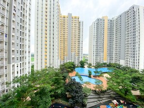 Un ensemble d’immeubles résidentiels de grande hauteur, doté d’une piscine centrale entourée de verdure et d’une aire de jeux.