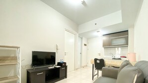 A modern living room with a flat-screen TV, a sofa, and a dining area with a table and chairs. - Elegant And Comfy 2Br Springlake Summarecon Bekasi Apartment Near Summarecon Mall (Bekasi)