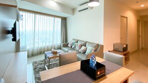 A modern living room with a sofa, a dining table, and a kitchen area. - Fancy And Nice 3Br At Grand Kamala Lagoon Apartment (Bekasi)