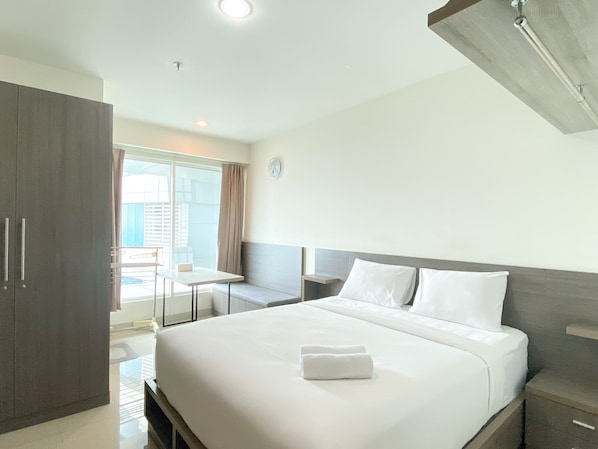 A hotel room with a bed, a bedside table, a wardrobe, and a window with curtains.