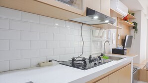 A modern kitchen with white tiles, a gas stove, a built-in oven, a sink, and wooden cabinets.