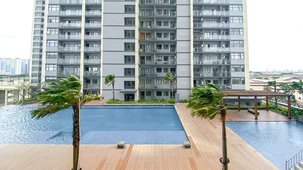 A modern apartment building with a rooftop pool area, including a wooden deck and palm trees.