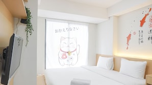 A hotel room with a bed, a TV, and a window with a cat illustration.