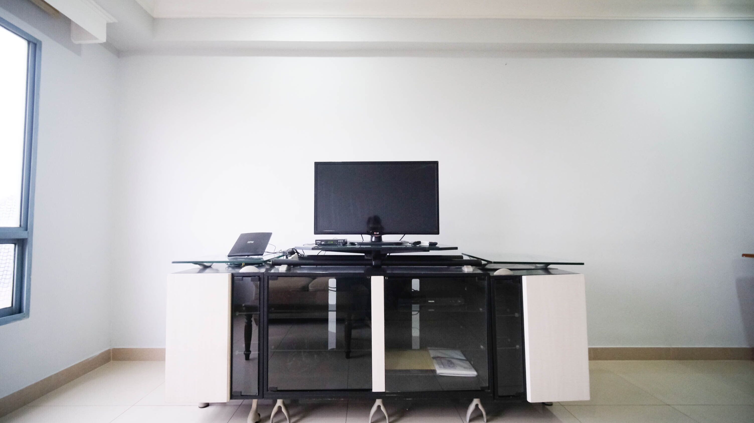 Un espacio de oficina moderno con un escritorio de vidrio, un monitor de pantalla plana y una computadora portátil.