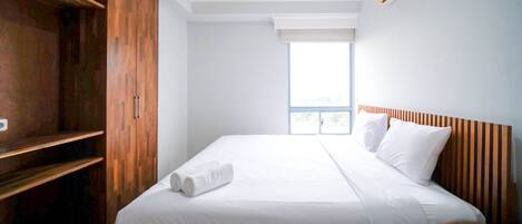 Una habitación de hotel con una cama grande, un armario de madera y una ventana con vistas.