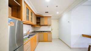 Een compacte keuken met houten kastjes, een roestvrijstalen koelkast en een betegelde achterwand.