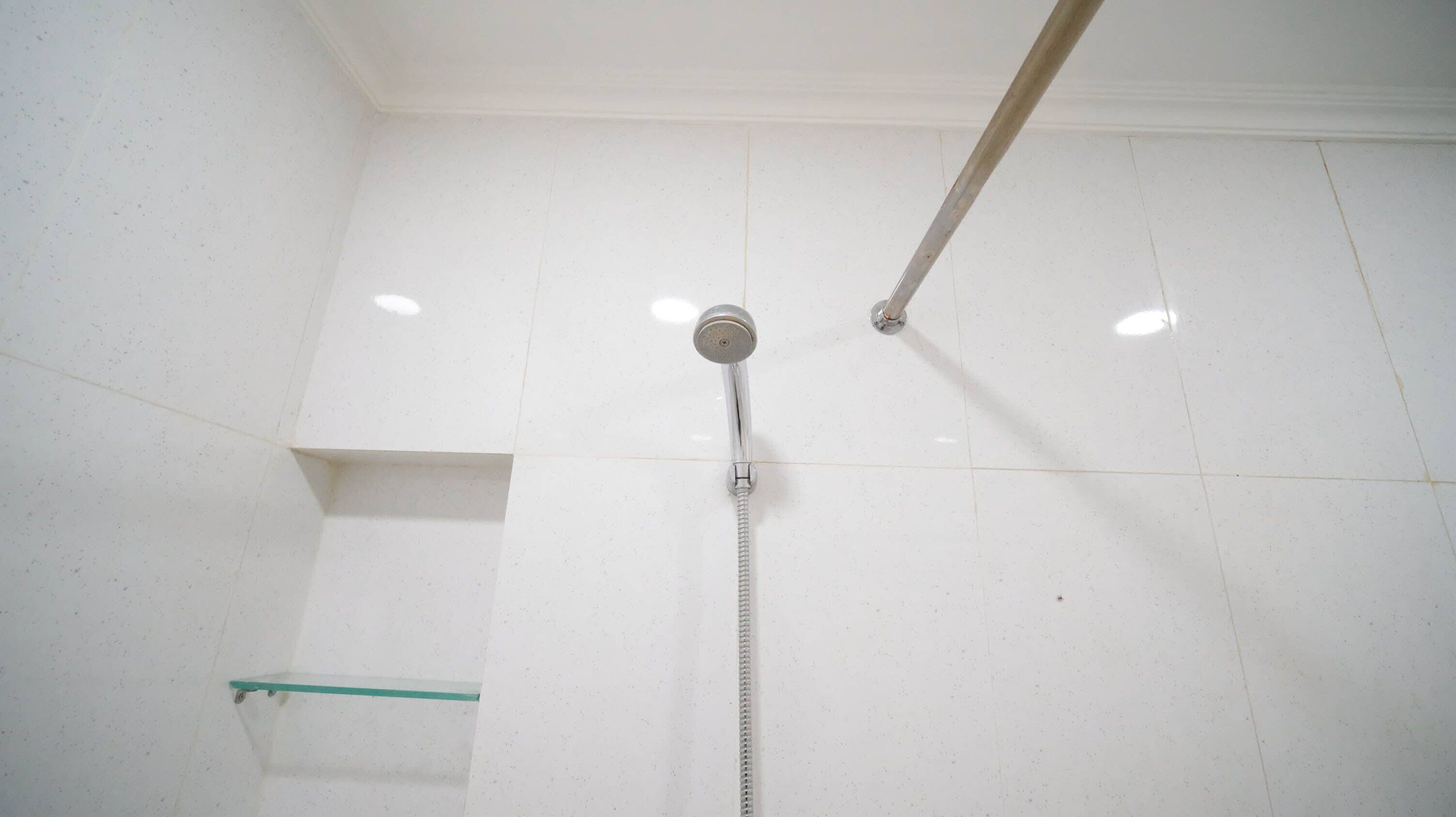 A shower with a chrome head and a flexible hose.