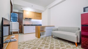 A compact living space with a kitchenette, a sofa, a television, and a water dispenser. - Well Designed 2Br Corner Transpark Cibubur Apartment (Bekasi)