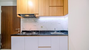 A kitchen with wooden cabinets, a marble backsplash, a gas stove, and a sink. - Well Designed 2Br Corner Transpark Cibubur Apartment (Bekasi)