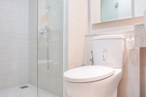 Une salle de bain moderne avec une douche en verre, des toilettes blanches et un mur recouvert de carreaux de marbre.