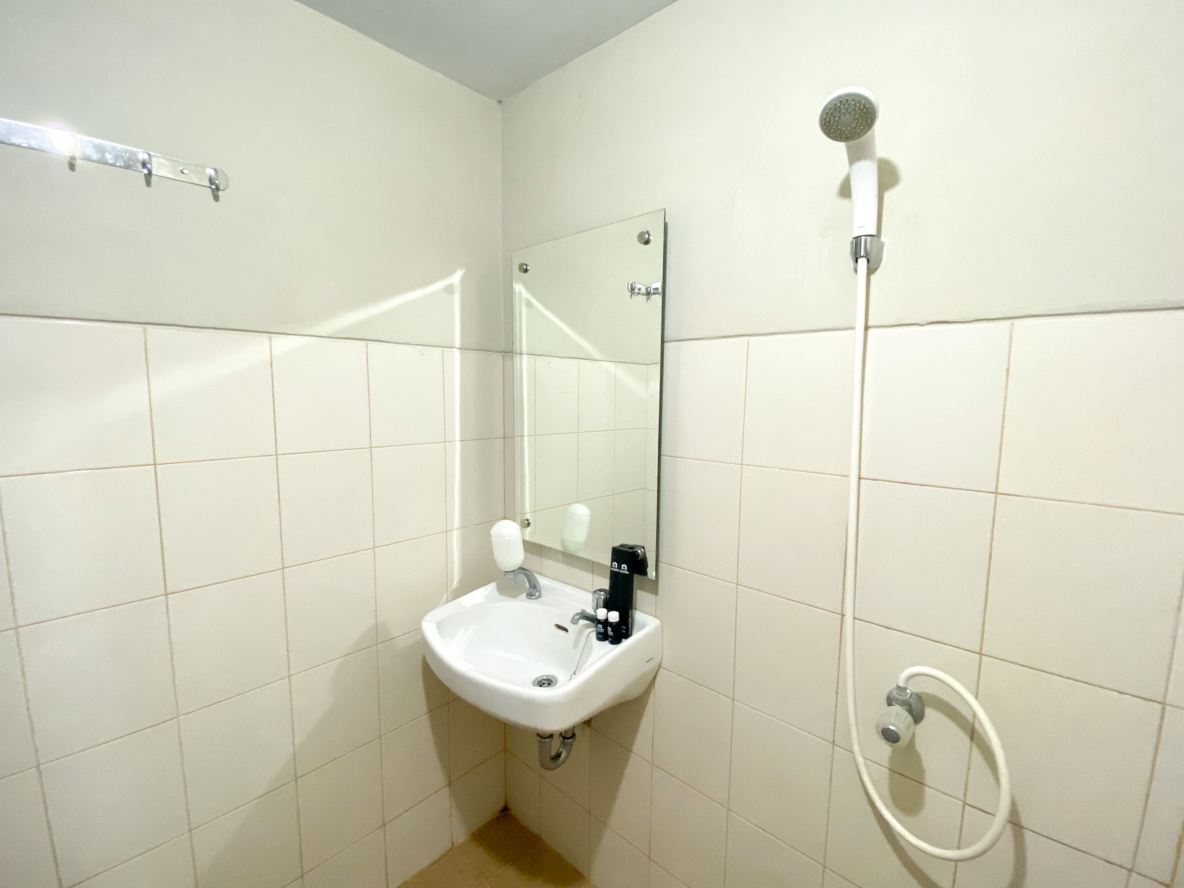 Un baño con lavamanos blanco, espejo y ducha.