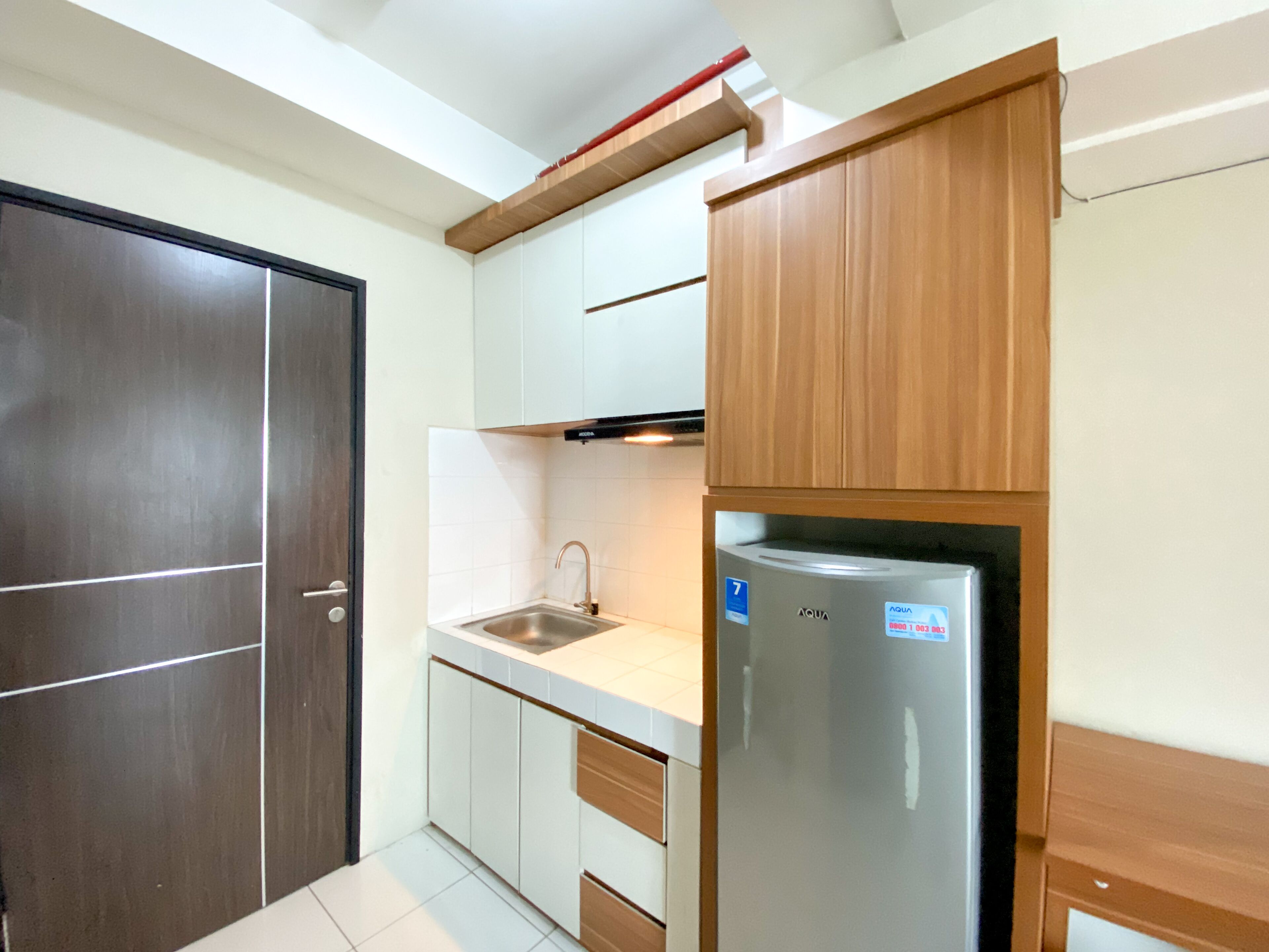 A compact kitchen with a built-in refrigerator, a sink, and wooden cabinets.