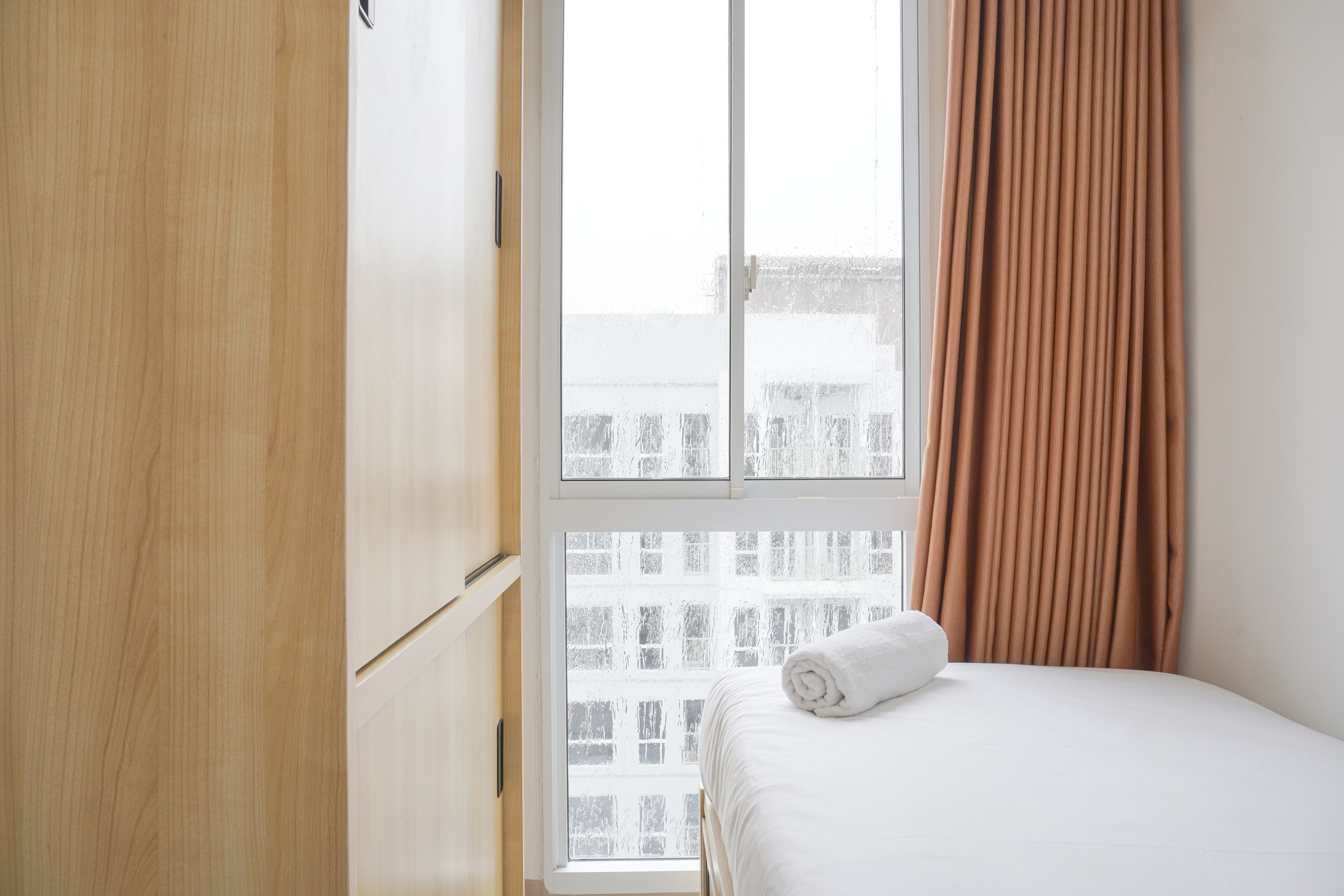 Een hotelkamer met een bed, een raam en een houten garderobe.