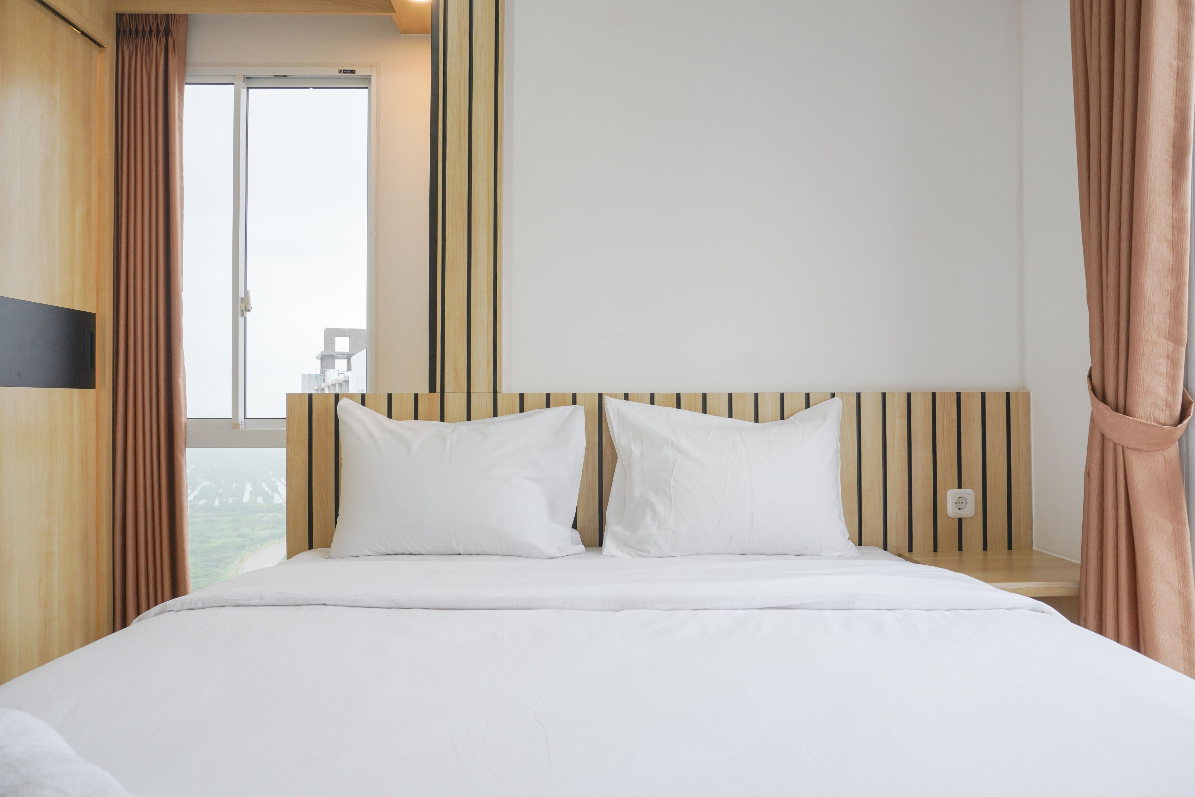 A hotel room with a large bed, wooden headboard, and a view of a balcony.