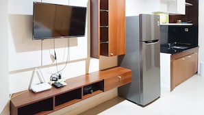 A modern kitchen with a built-in TV, a stainless steel refrigerator, wooden cabinets, and a white countertop. - Nice And Comfortable Studio At Vida View Makassar (Makassar)