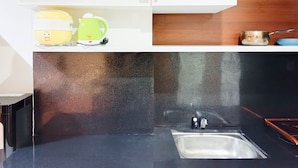 A kitchen with a black countertop, a stainless steel sink, and a white cabinet above. - Nice And Comfortable Studio At Vida View Makassar (Makassar)