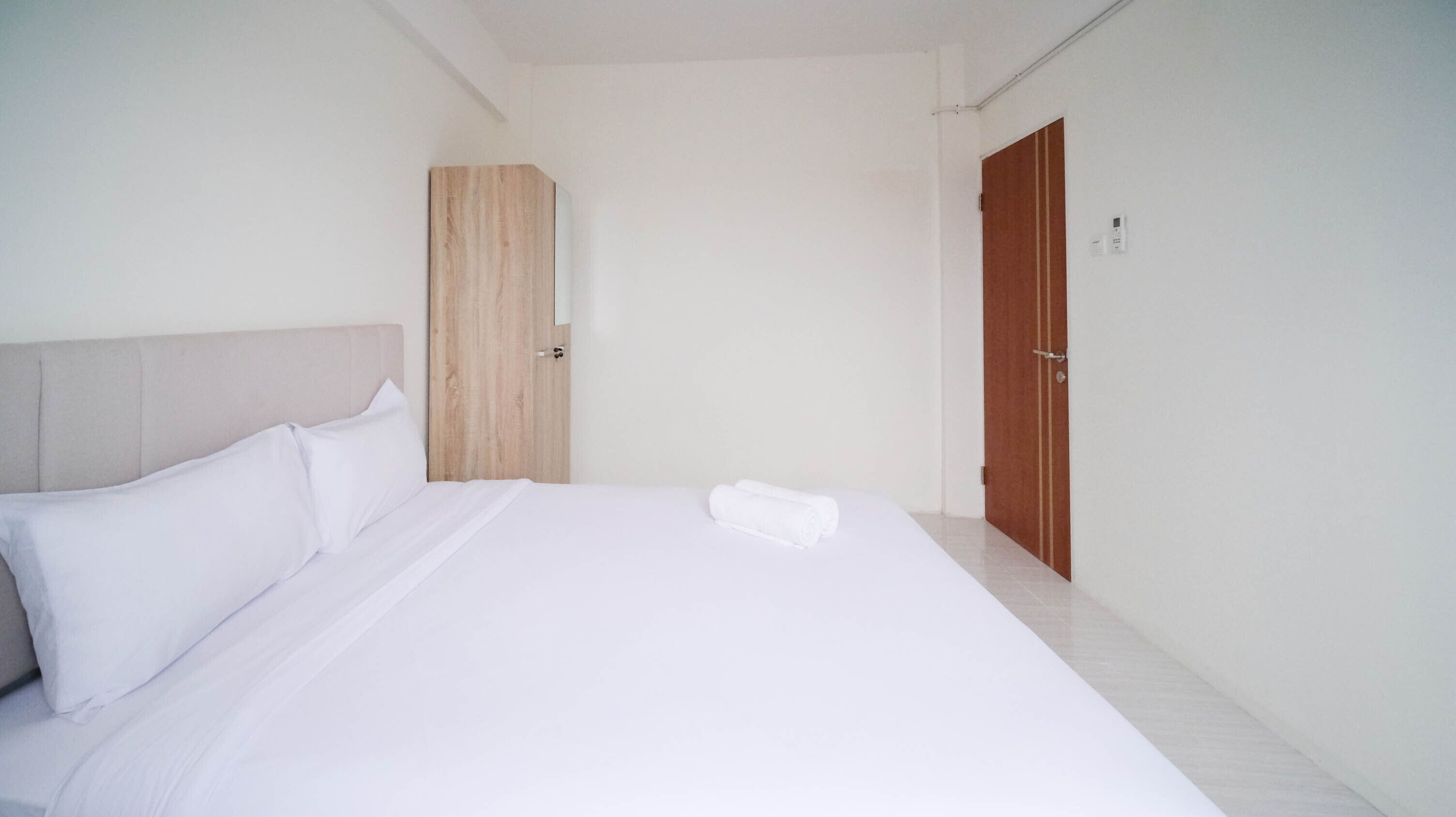 A hotel room with a large bed, a wooden wardrobe, and a door.