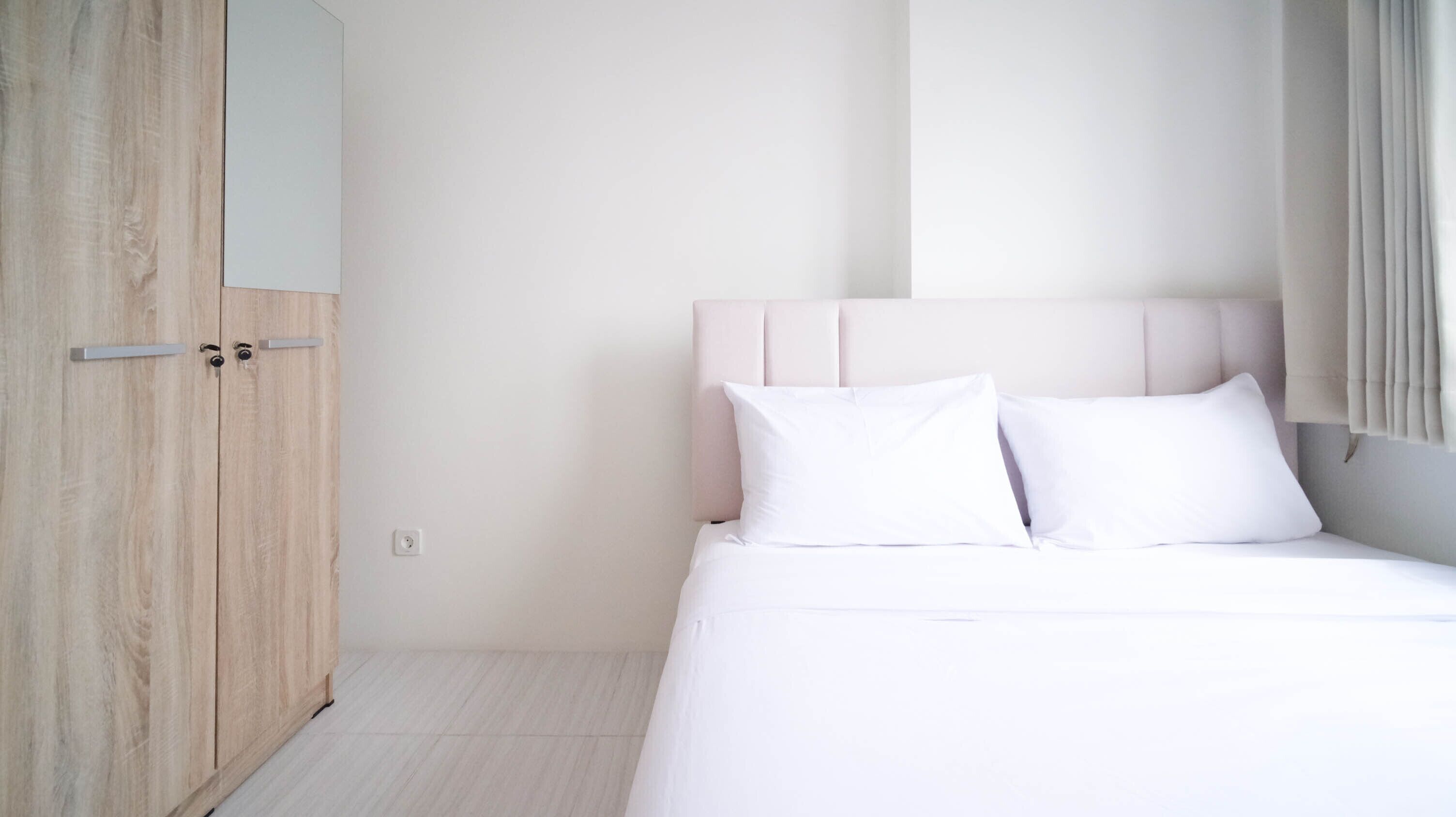 A bedroom with a bed, a wardrobe, and a window with curtains.