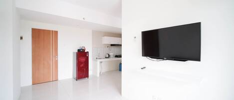 A modern kitchen with white cabinets, a red refrigerator, and a flat-screen TV mounted on the wall.