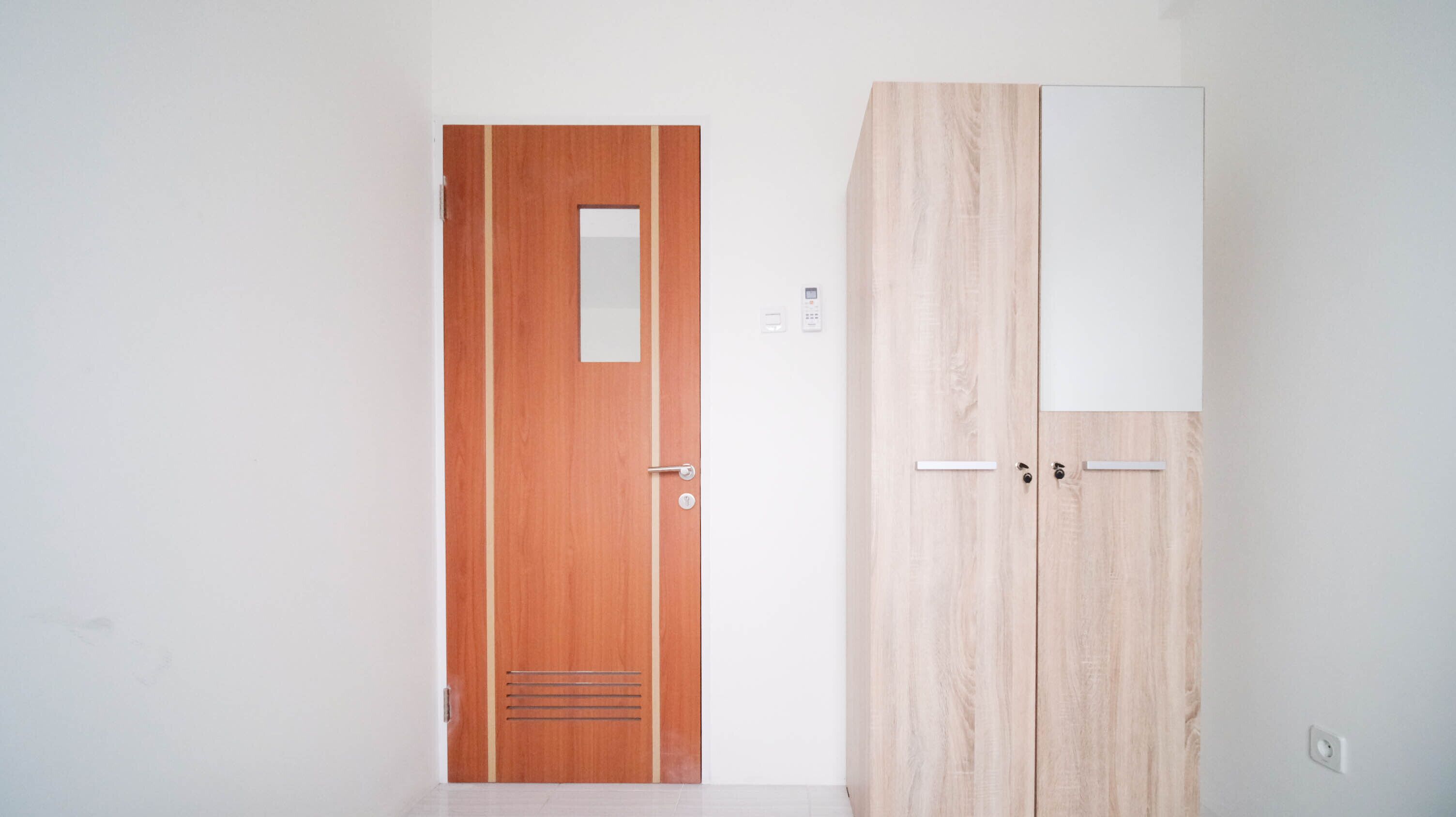 A room with a wooden door and a wardrobe with a white panel.