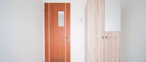 A room with a wooden door and a wardrobe with a white panel.