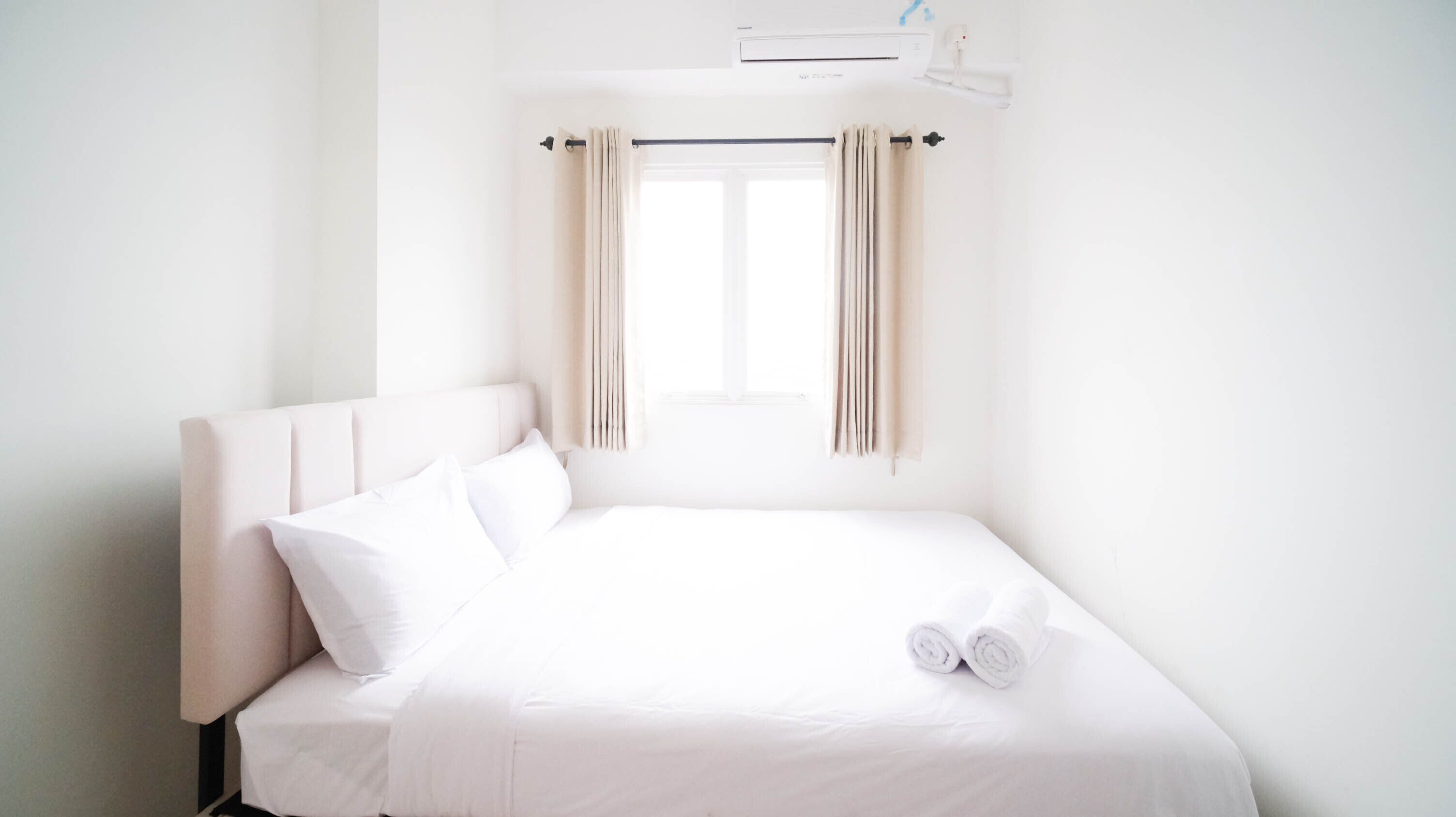 A white room with a bed, a window, and a ceiling fan.