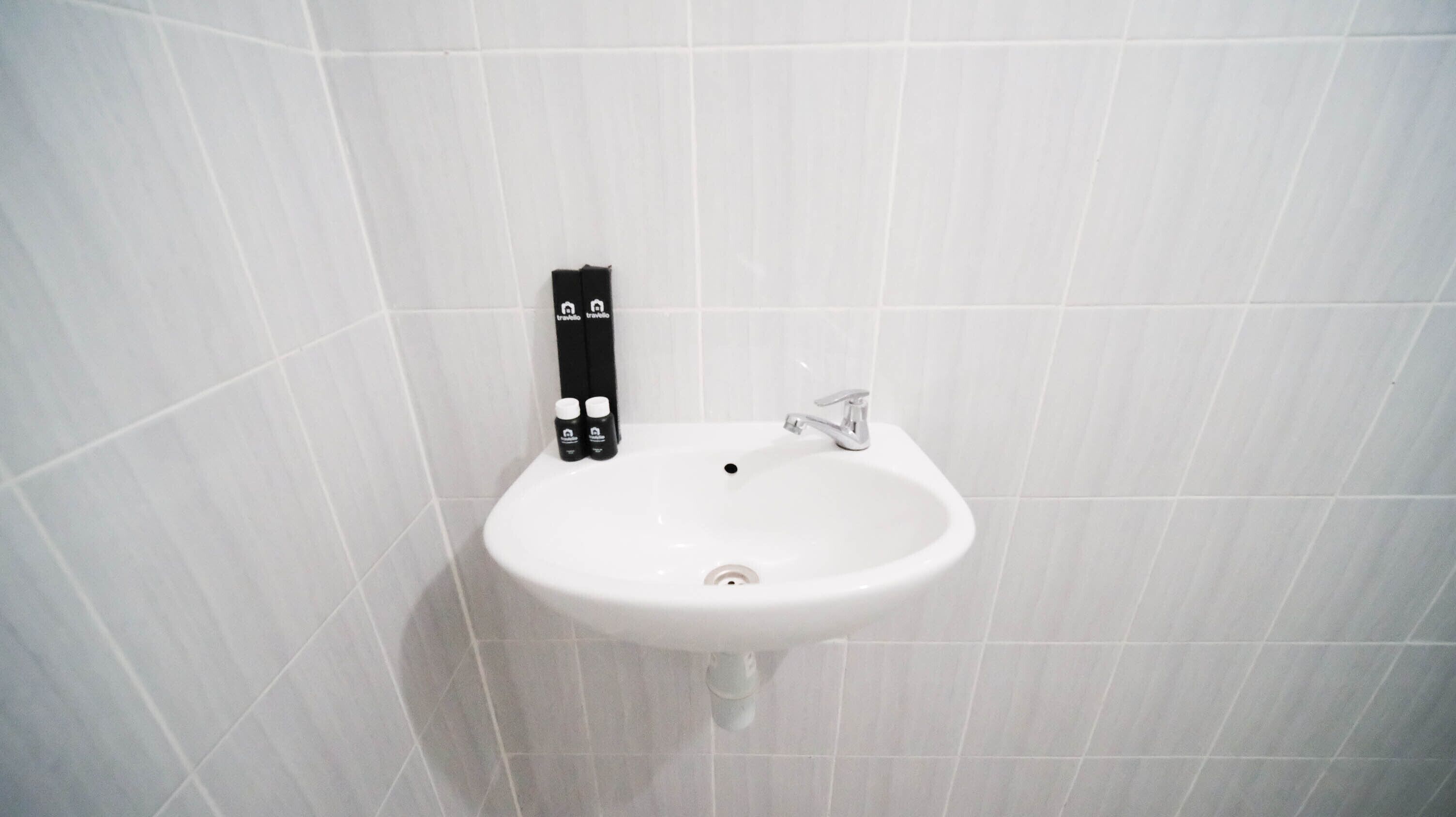 A white sink with a faucet and a soap dispenser mounted on the wall.