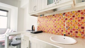 Een moderne keuken met een wit aanrecht, een spoelbak en een kleurrijke mozaïekachterwand.