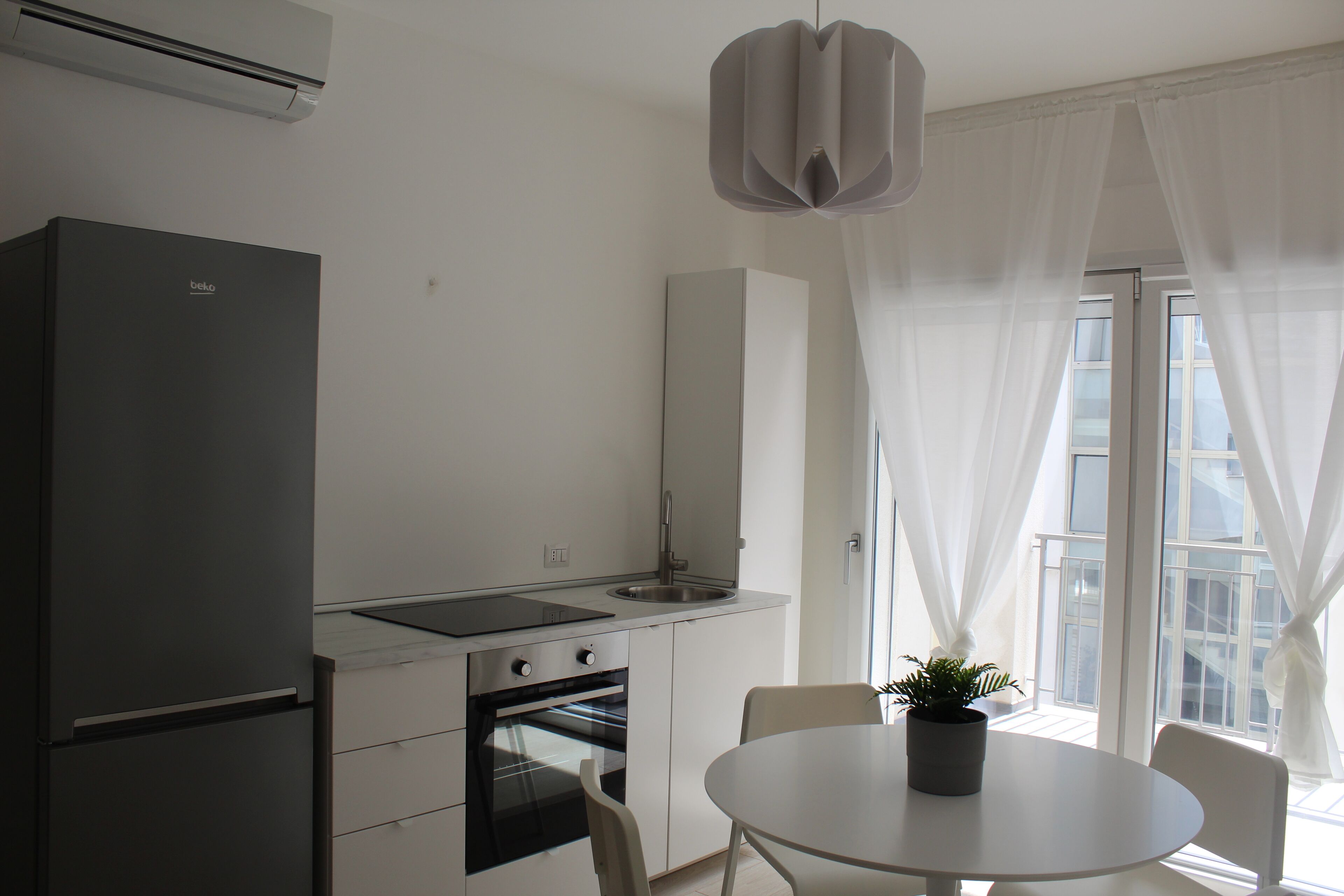 Una cocina moderna con refrigerador, horno, pileta y comedor con mesa y sillas.