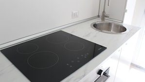 A modern kitchen with a black induction cooktop, a stainless steel sink, and a white marble countertop. - Virgilio 82 - Penthouse With Terrace (Trapani)