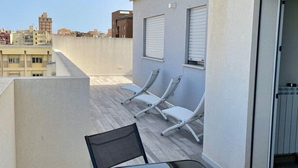 A rooftop terrace with a table and chairs, a sliding door, and a view of the cityscape. - Virgilio 82 - Penthouse With Terrace (Trapani)