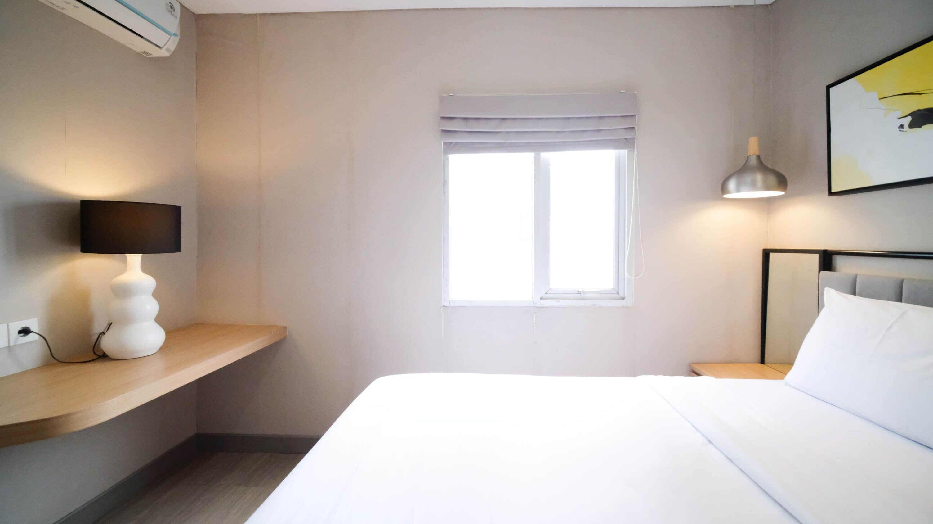 Une chambre d’hôtel avec un lit, une table de chevet, une lampe et une fenêtre donnant sur un paysage agréable.