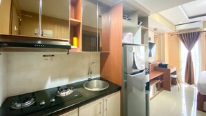 A modern kitchen with a gas stove, sink, and stainless steel refrigerator.