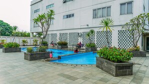 Un bâtiment moderne doté d’une piscine, entourée de jardinières et de coins salons extérieurs.