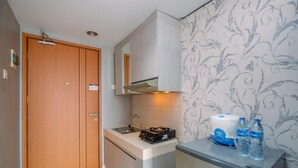 Une petite cuisine compacte dotée d’une porte en bois, d’un four encastré, d’un évier et d’un réfrigérateur.