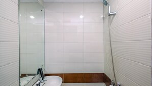 Une salle de bain avec un lavabo blanc, un miroir et une douche.