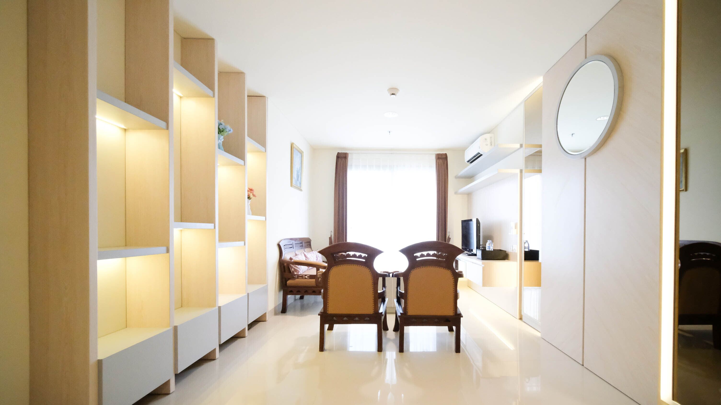 A hotel room with a dining area, a TV, and a large mirror.