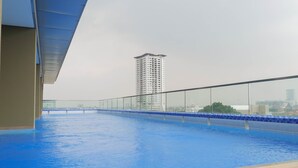 Ein Pool auf dem Dach mit freiem Blick auf ein hohes Gebäude im Hintergrund.