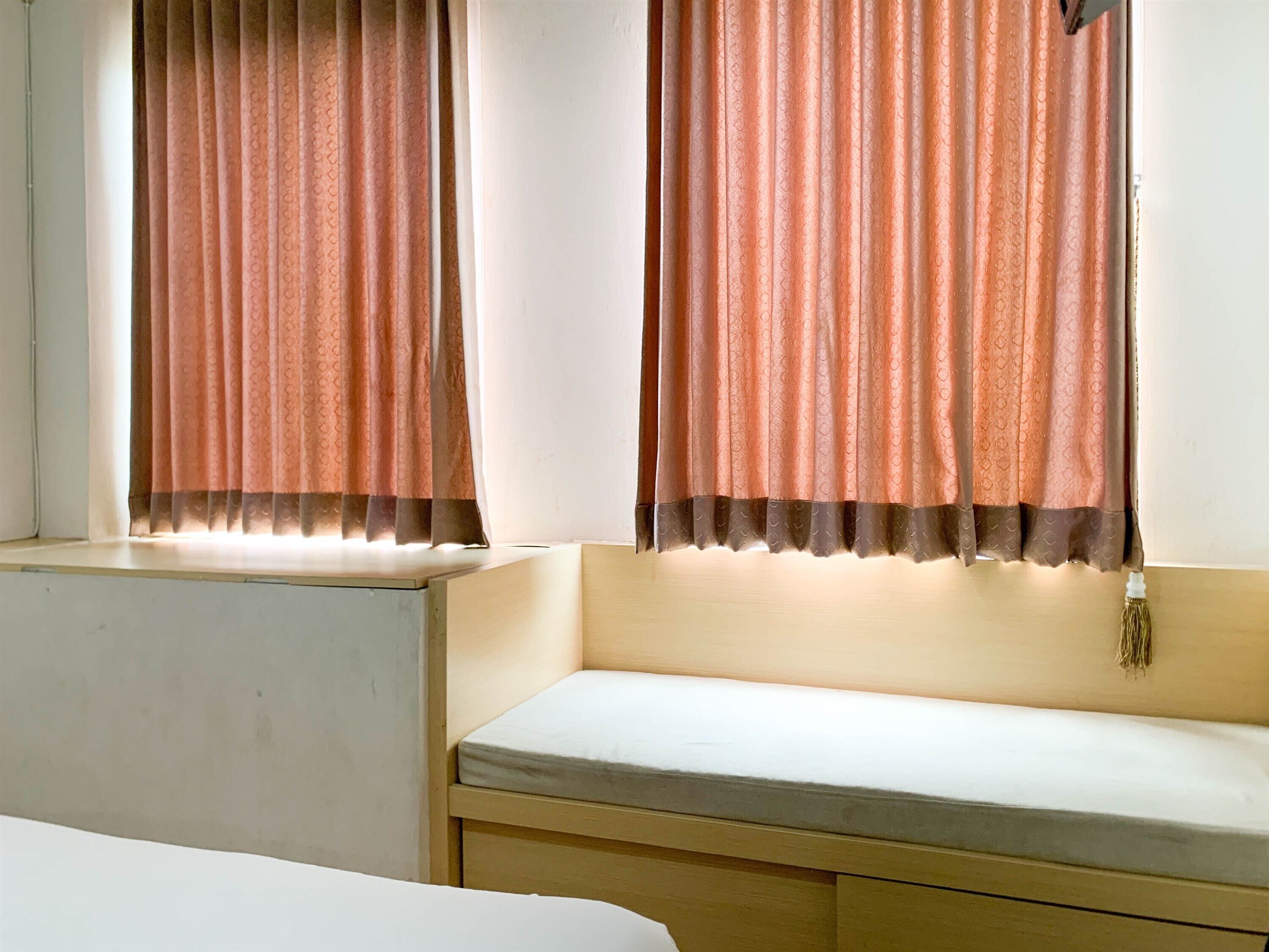A room with a window, a bench, and a bed.