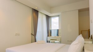 Hotellihuone, jossa on sänky, työpöytä, tuoli ja peili.