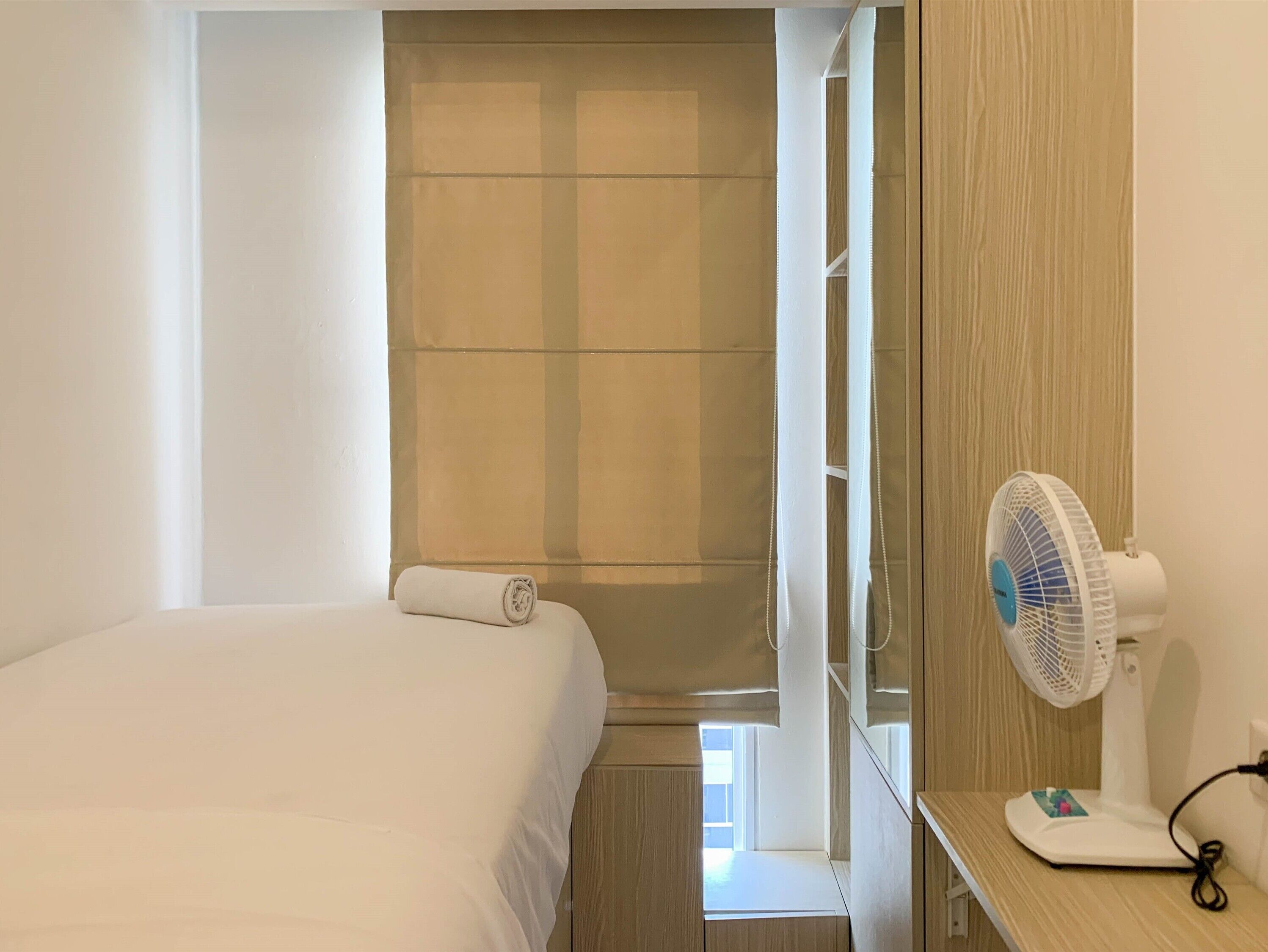 A bedroom with a bed, a fan, and a window with curtains.