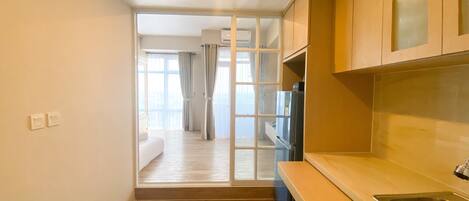 A narrow kitchen with a built-in refrigerator, a sink, and a window overlooking a balcony.
