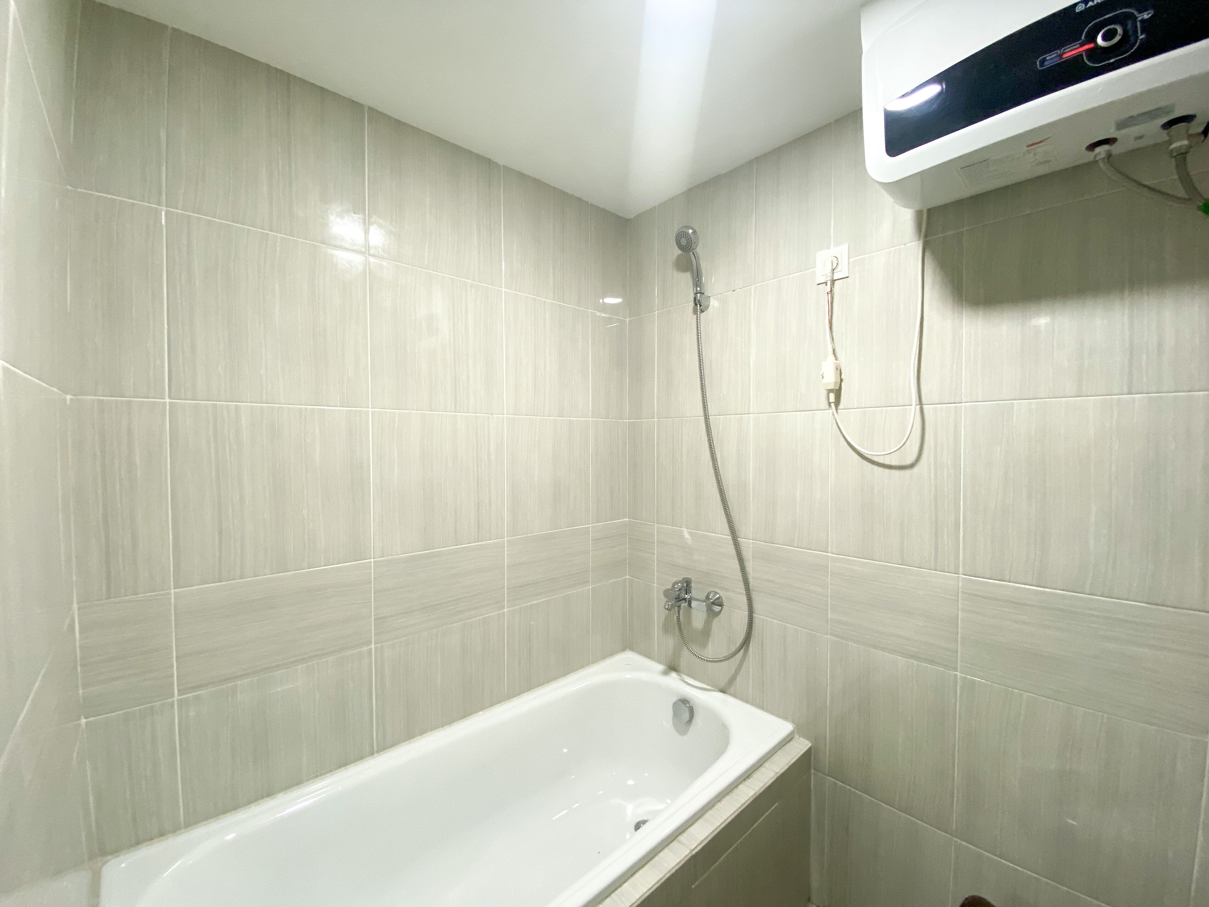 A bathroom with a bathtub, a shower, and a control panel on the wall.